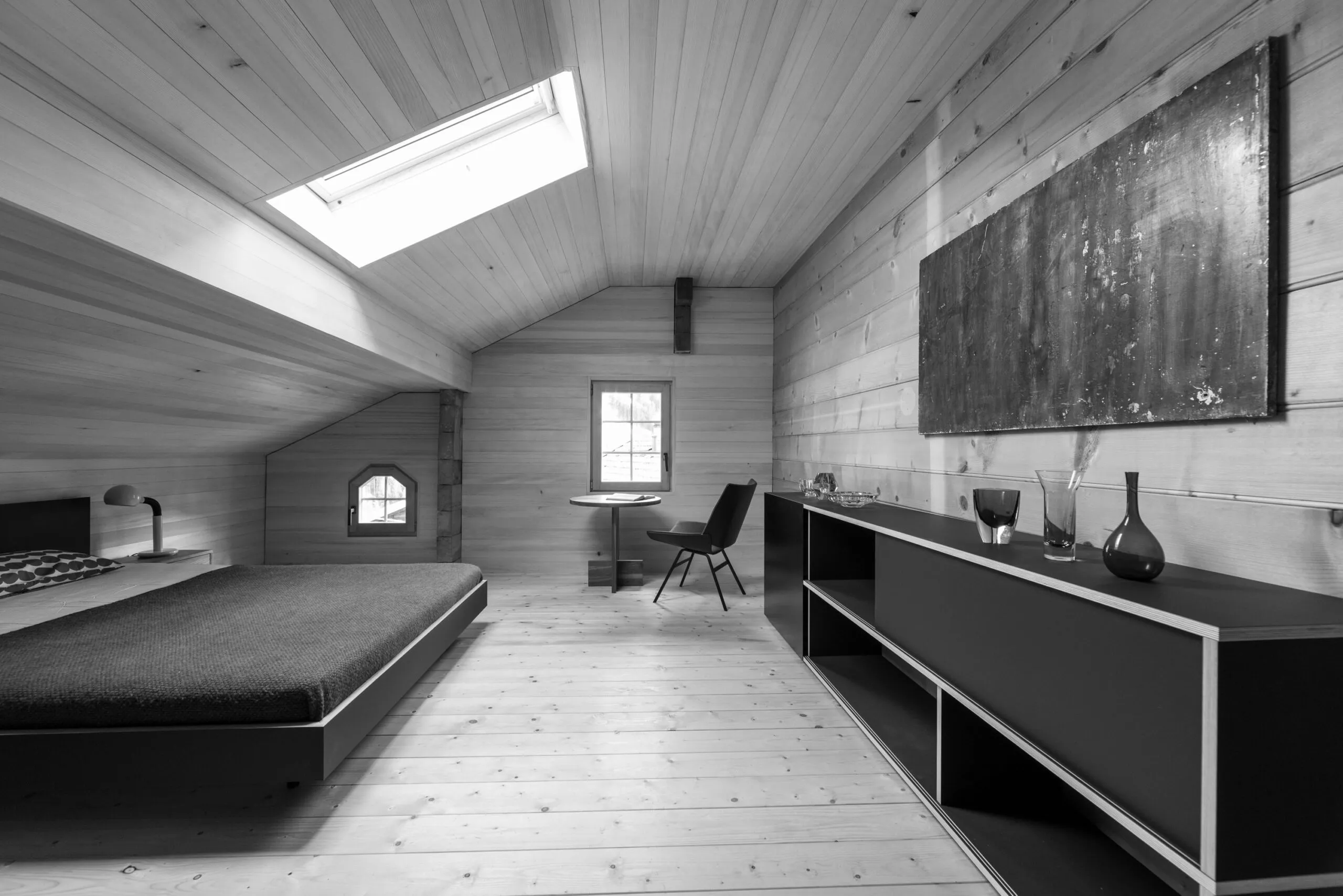 Strickbau: Dachzimmer mit Dachfenster, Bett und niedrigem Sideboard