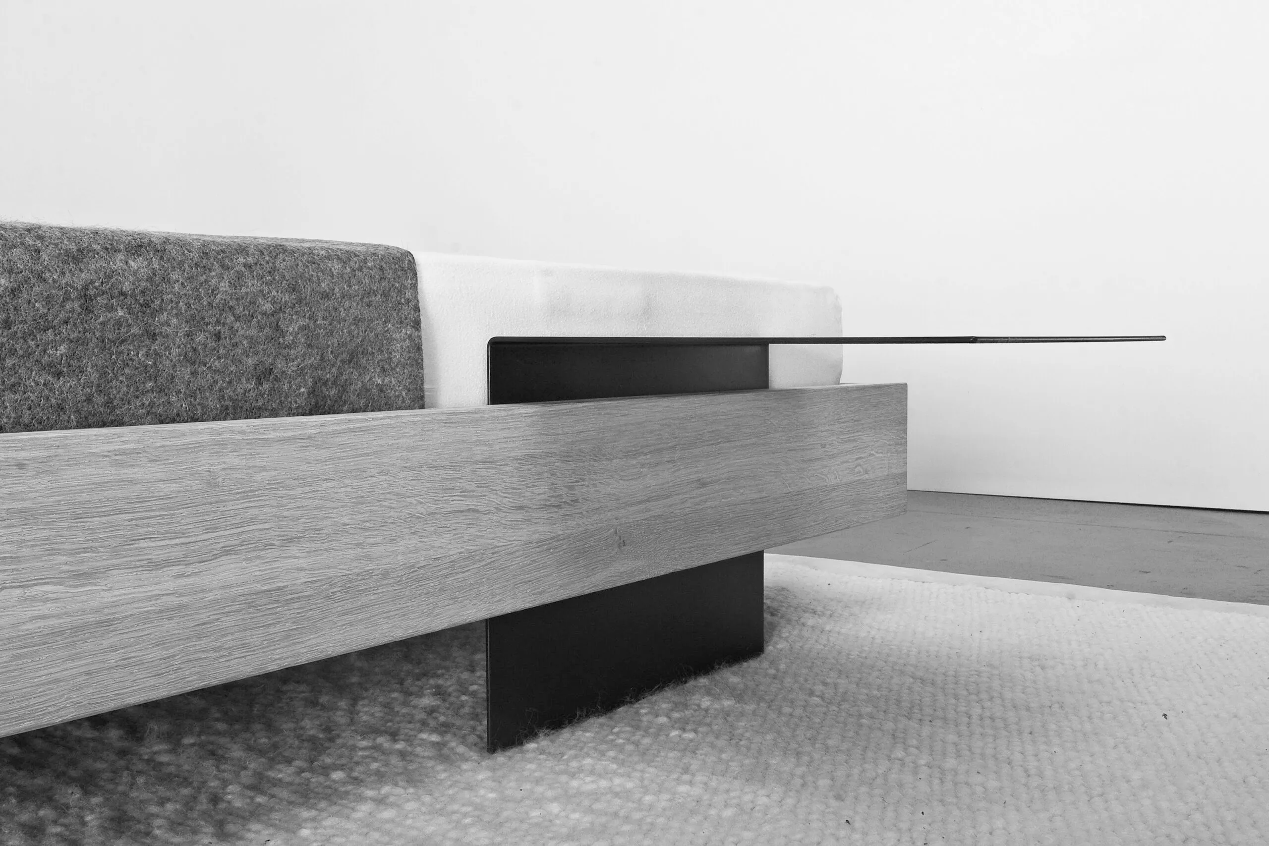 Möbel von Sanktjohanser: Sofa mit Holzzarge, grauem Polster und schwarzer Ablage, Detail