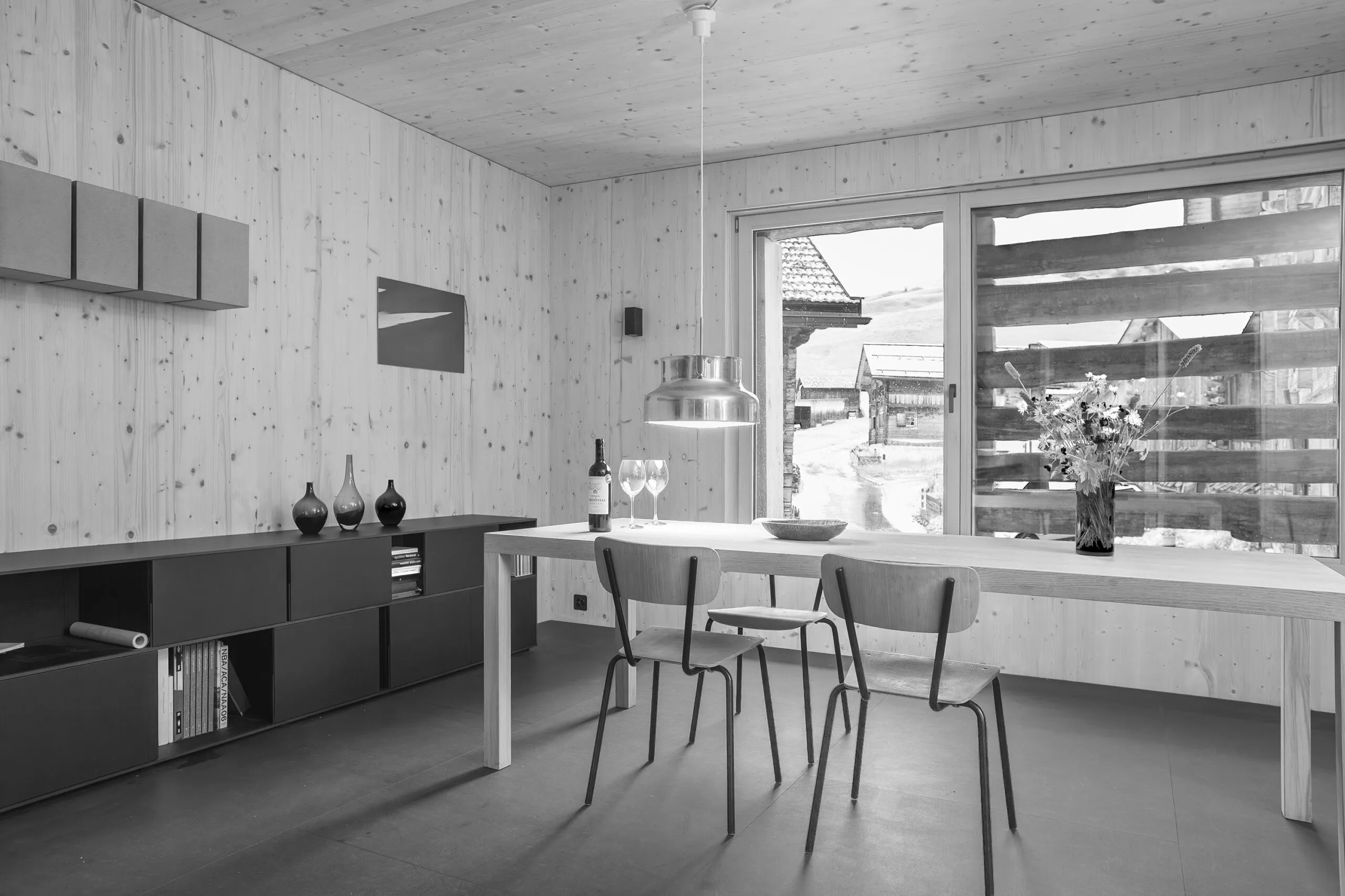Stallumbau: Esstisch und Sideboard vor einem grossen Fenster mit Blick ins Dorf